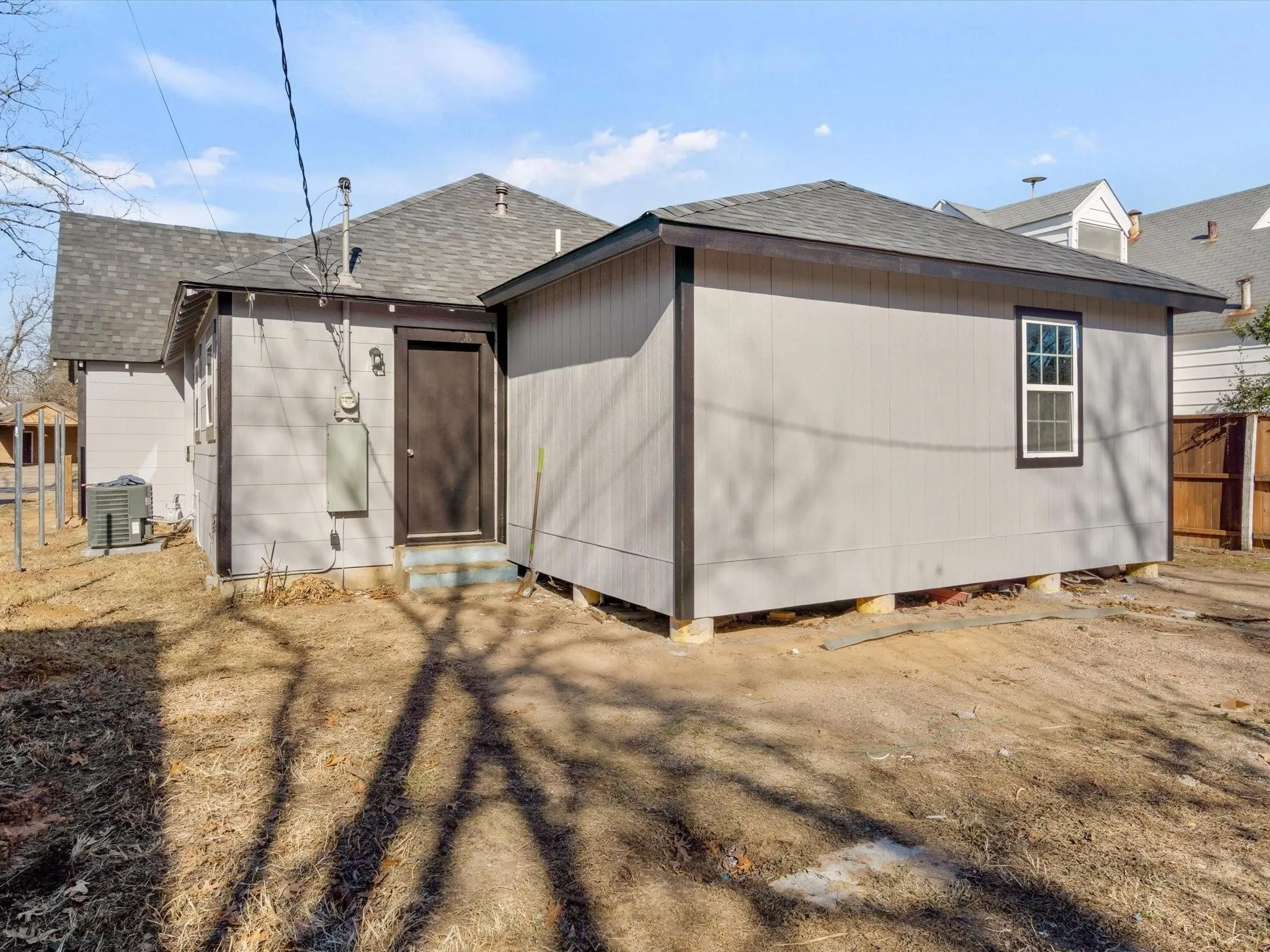 Exterior features include light gray siding, dark trim, a dark asphalt shingle roof, and a visible exterior window
