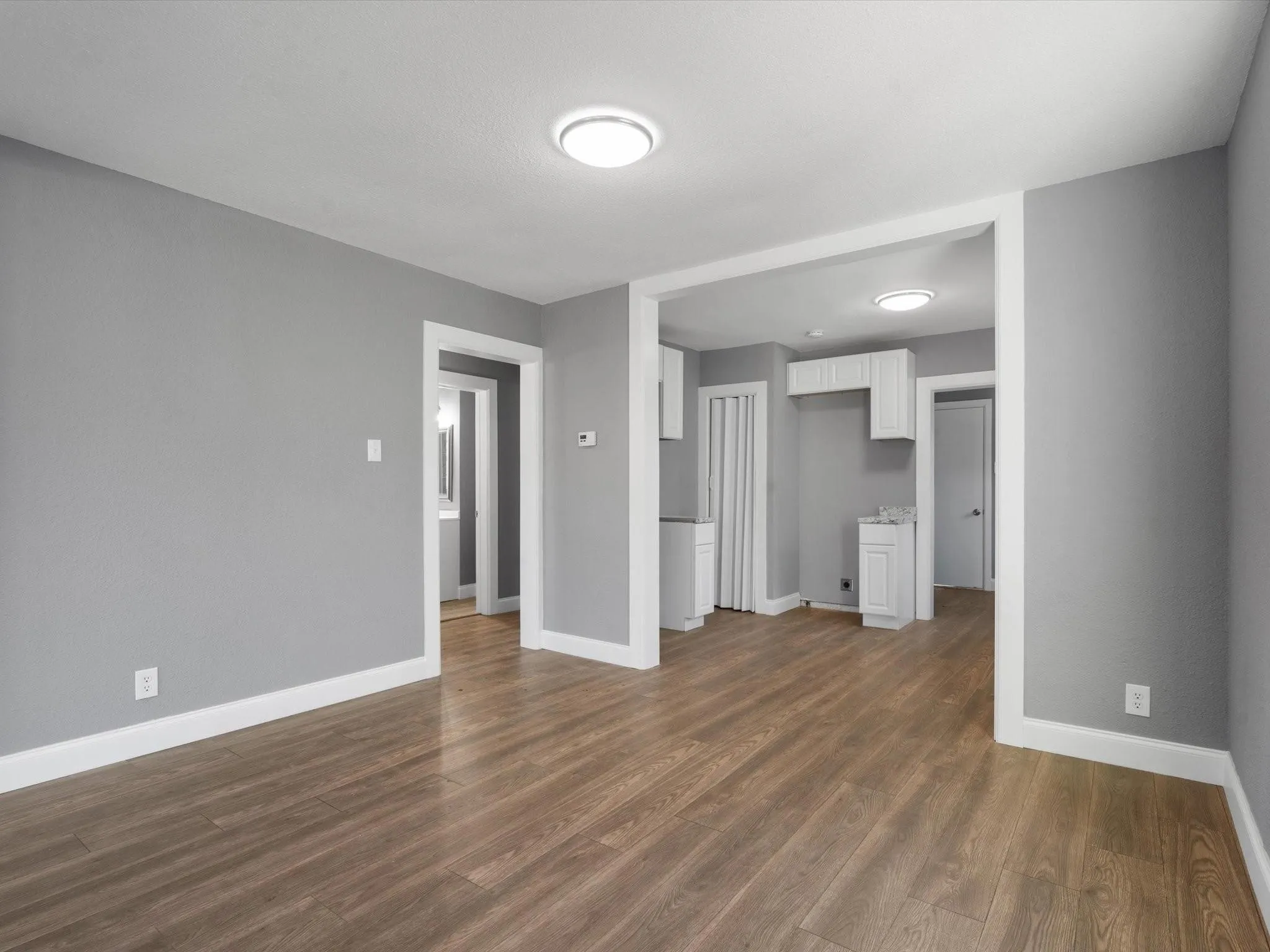 Wood-finish flooring, recessed ceiling lighting, light gray wall color, white trim, and white cabinetry