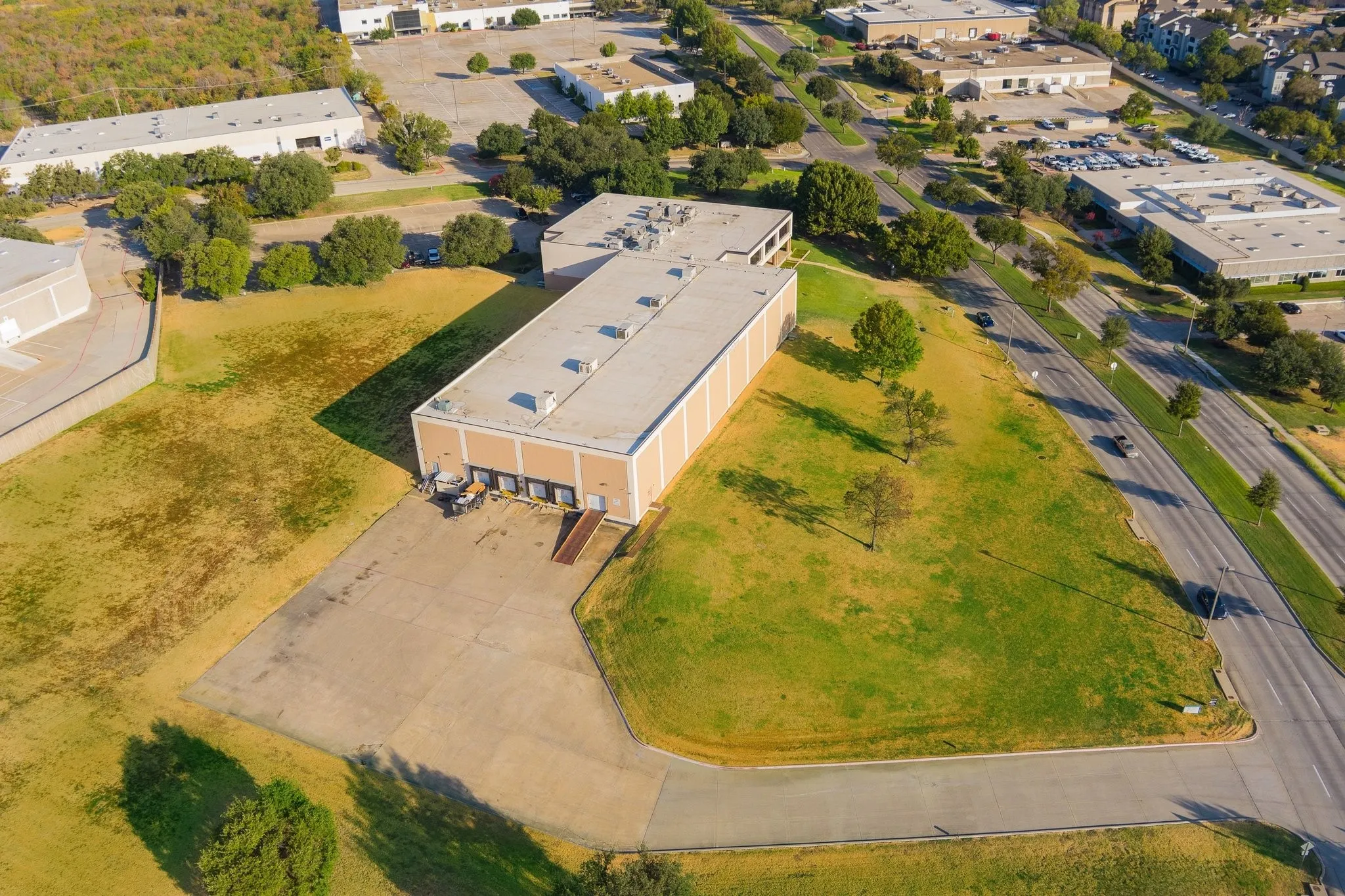 Commercial building with multiple loading docks, an expansive paved lot, and a large grassy area