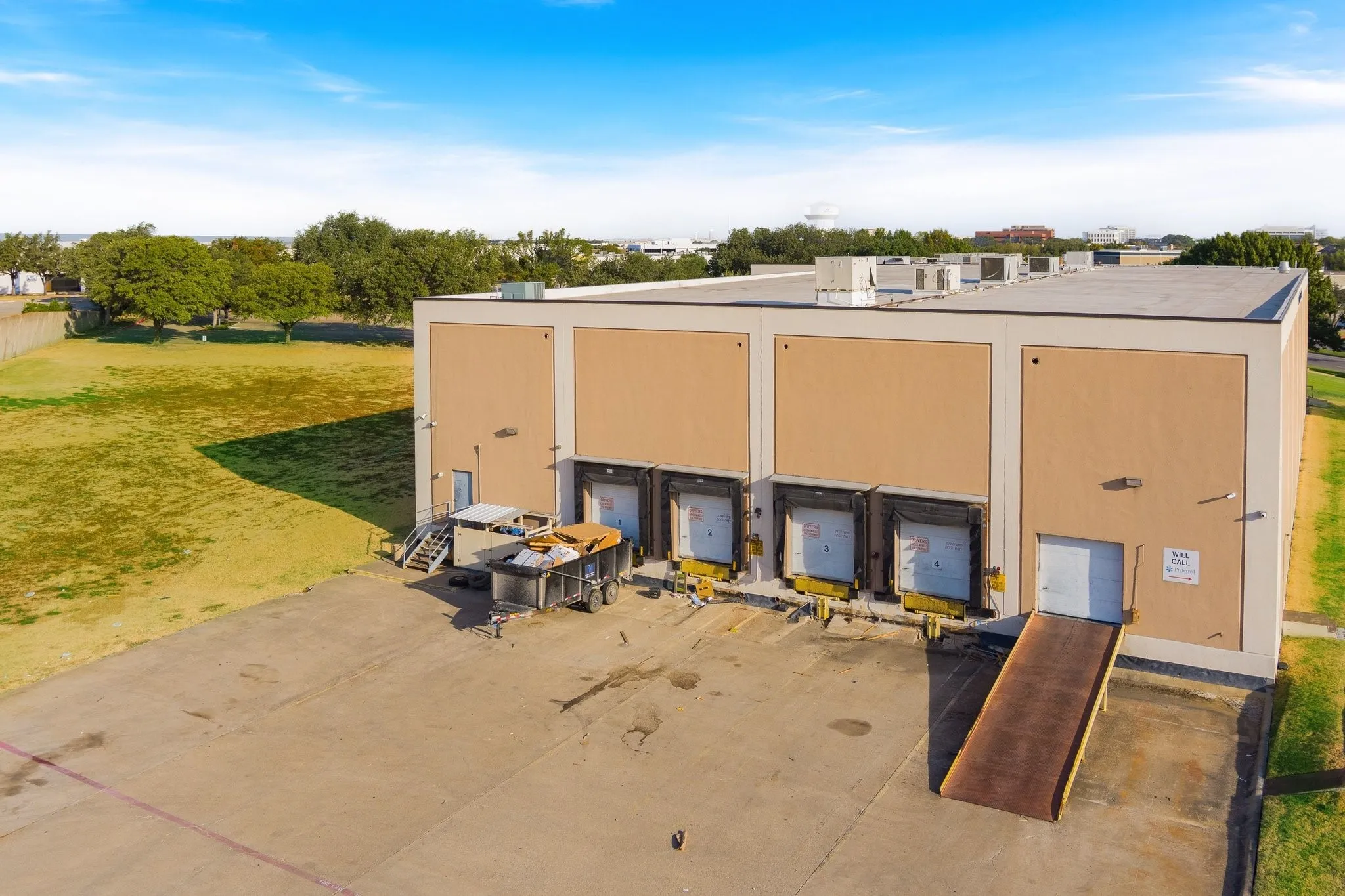 Commercial building with multiple loading docks, a dedicated ramp entrance, a flat roof, and an expansive paved lot