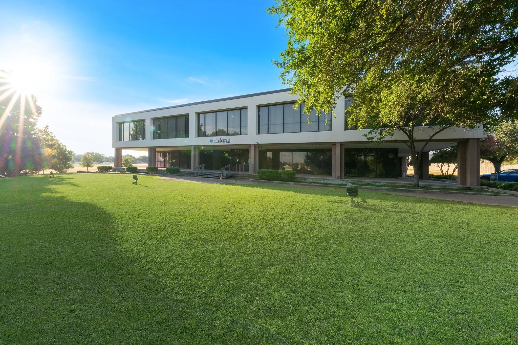 Modern architecture building with a landscaped lawn, expansive windows, and a portico entrance