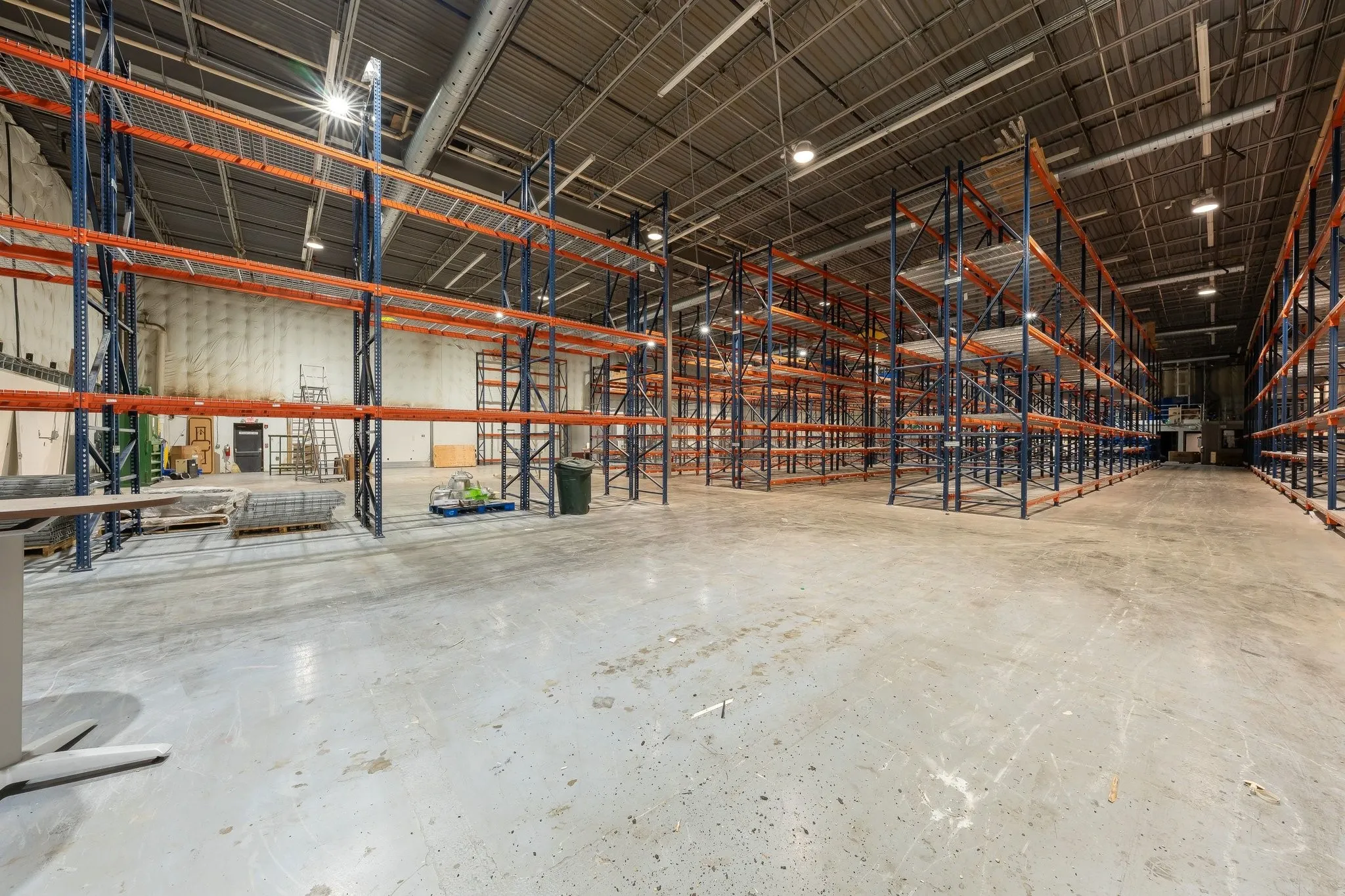 High-bay warehouse space featuring metal racking systems, concrete flooring, and overhead lighting