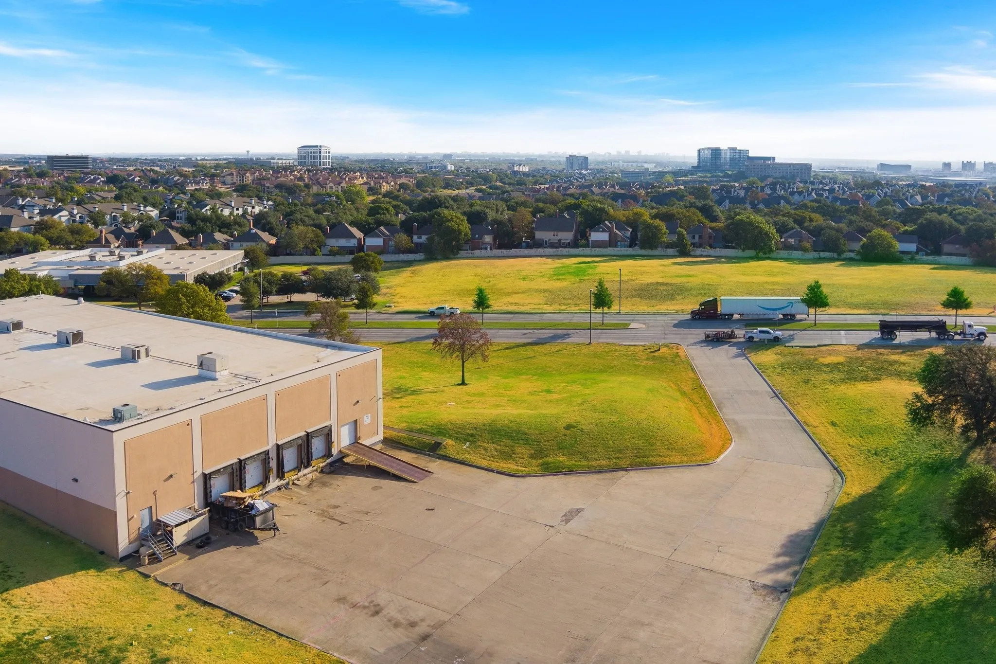 Industrial building featuring multiple loading docks, a concrete parking area, and a flat roof