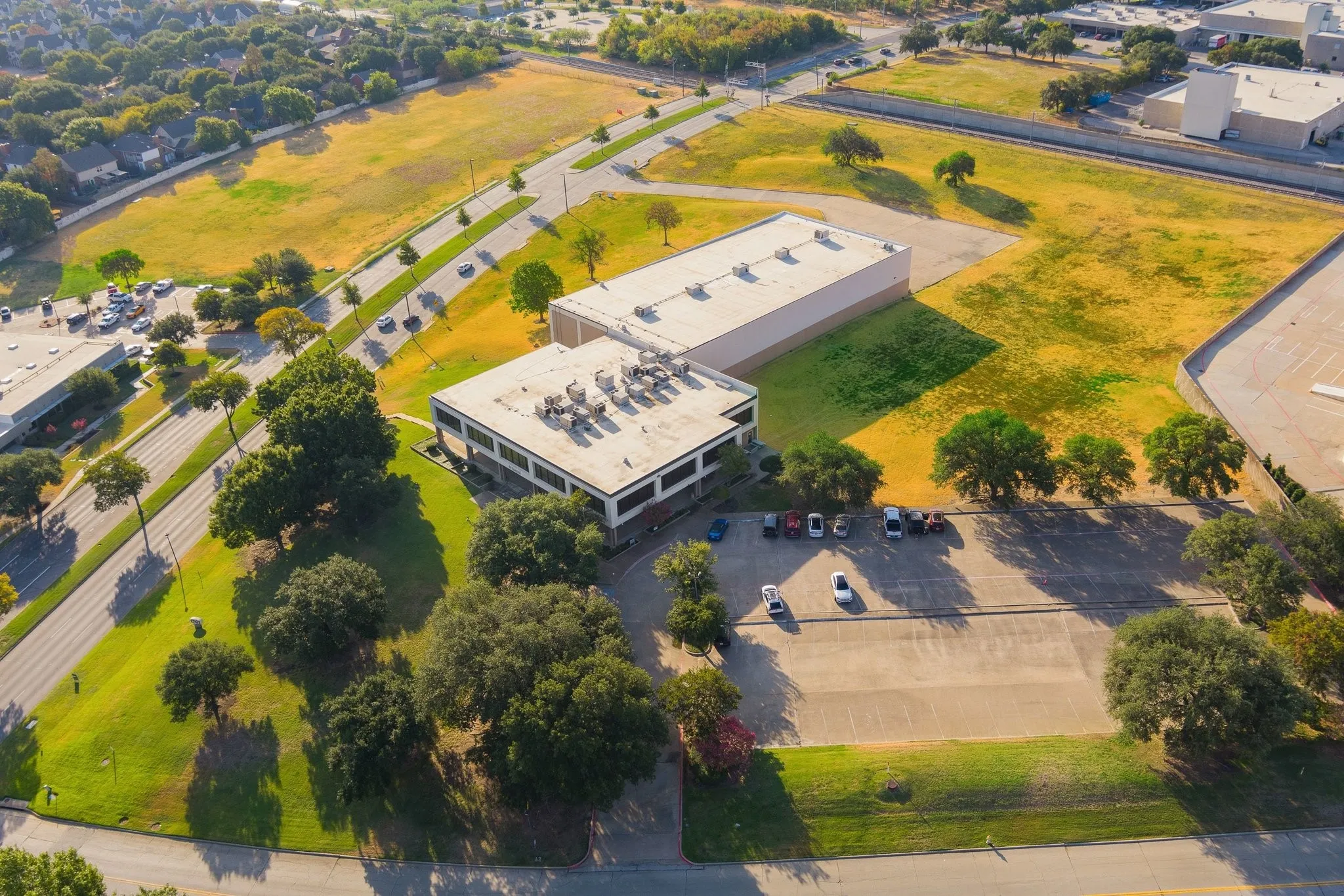 Expansive commercial property featuring two structures, paved parking areas, and surrounding green spaces