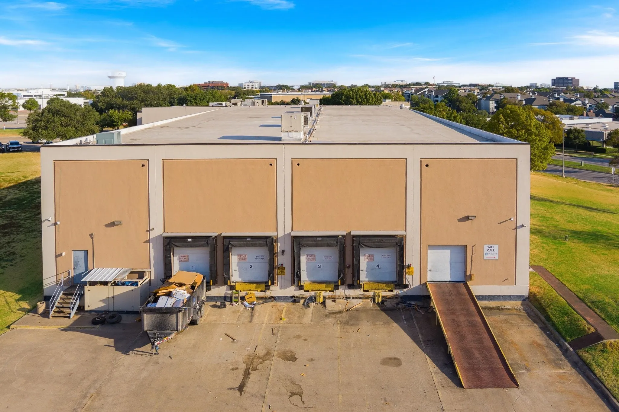 Commercial building featuring loading dock doors, an additional ground-level access door with ramp, and a flat roof