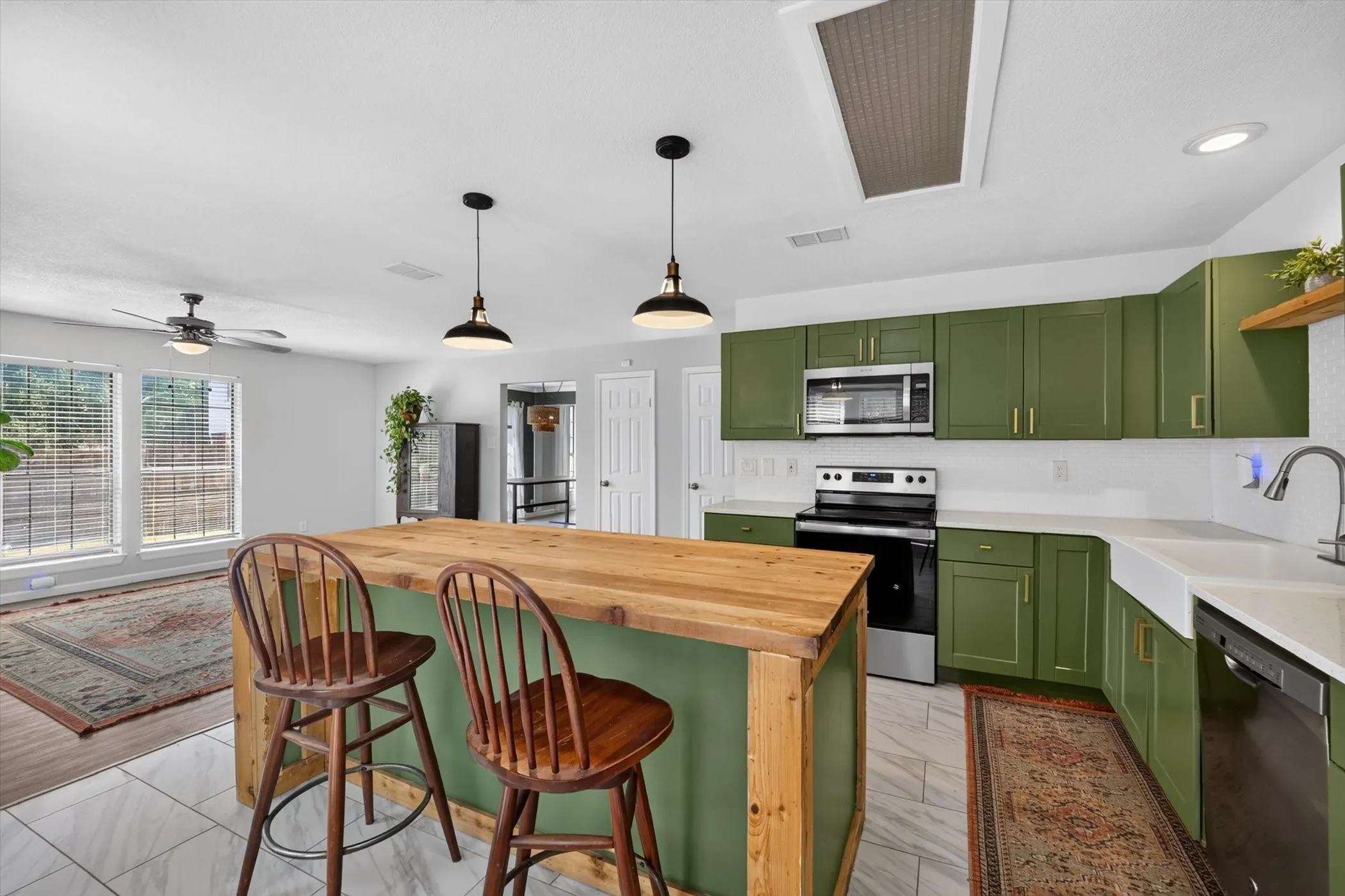 Kitchen island with a wood-finish countertop, green base, and pendant lighting