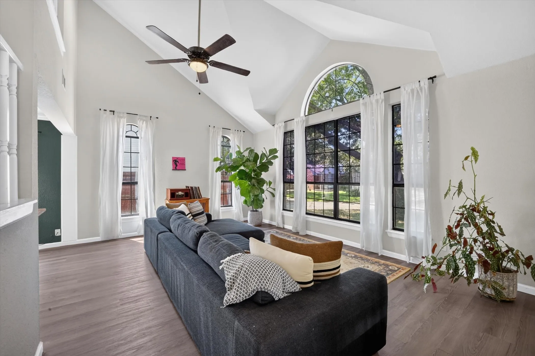 Vaulted ceilings with ceiling fan, wood-finish flooring, and arched window