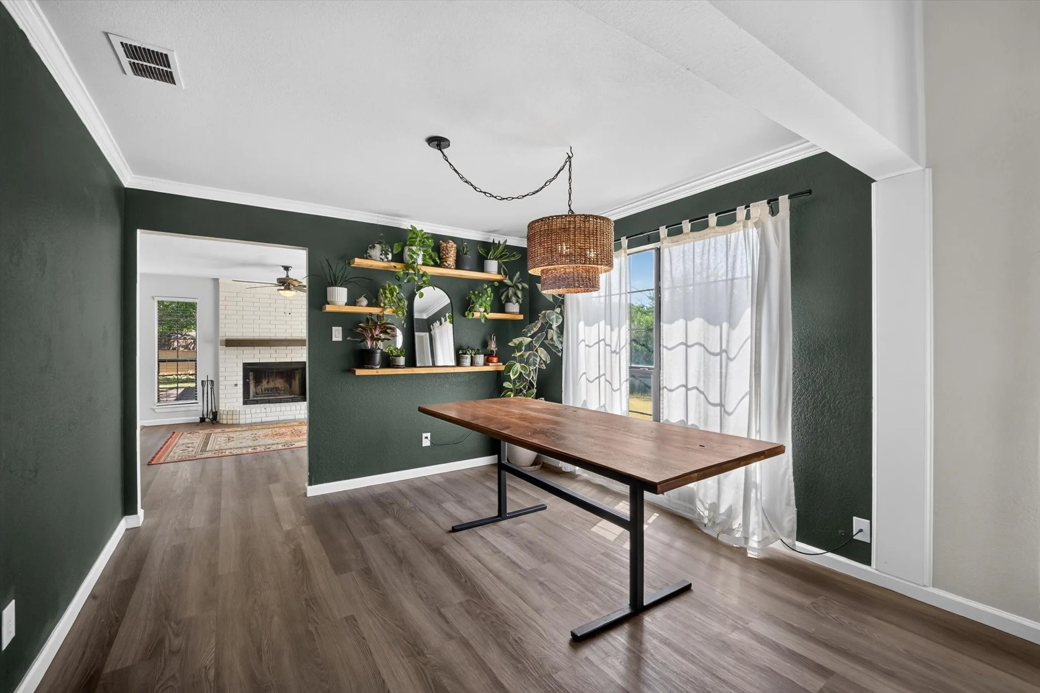 Open-concept living space with wood-finish flooring, a contemporary woven pendant light fixture, and a window with white curtains