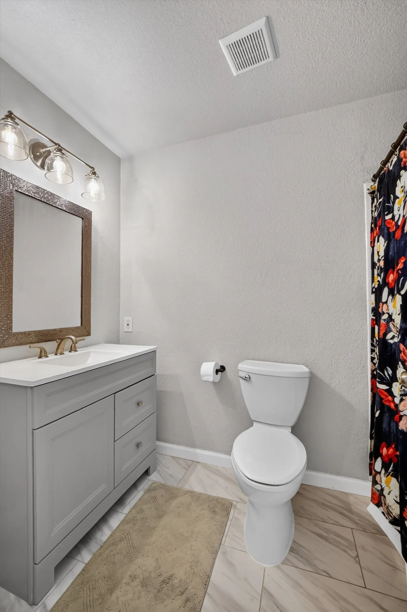 Single vanity with a white countertop, undermount sink, and brushed gold faucet
