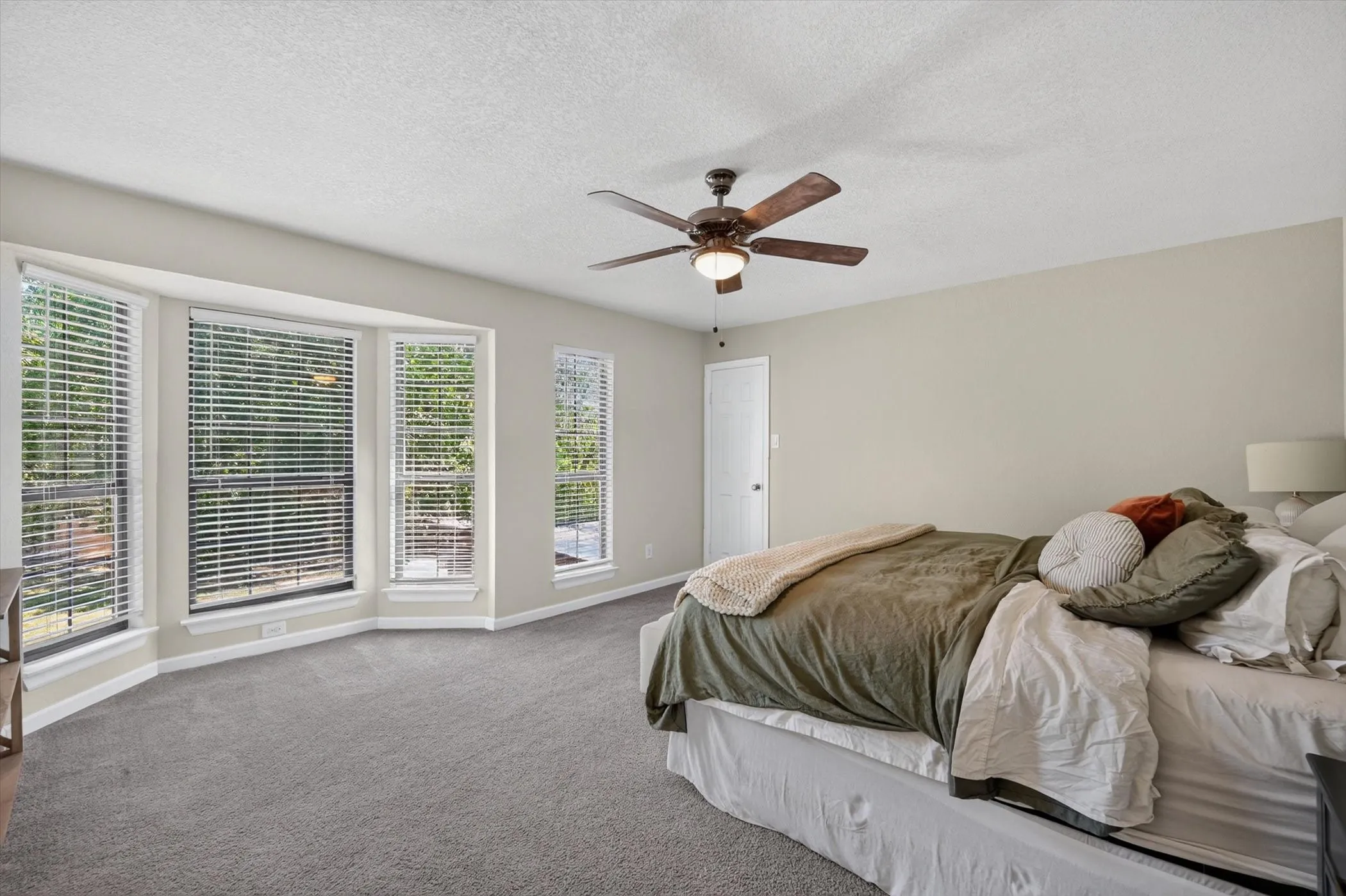 Neutral wall color, ceiling fan with light fixture, gray carpeting, and multiple windows