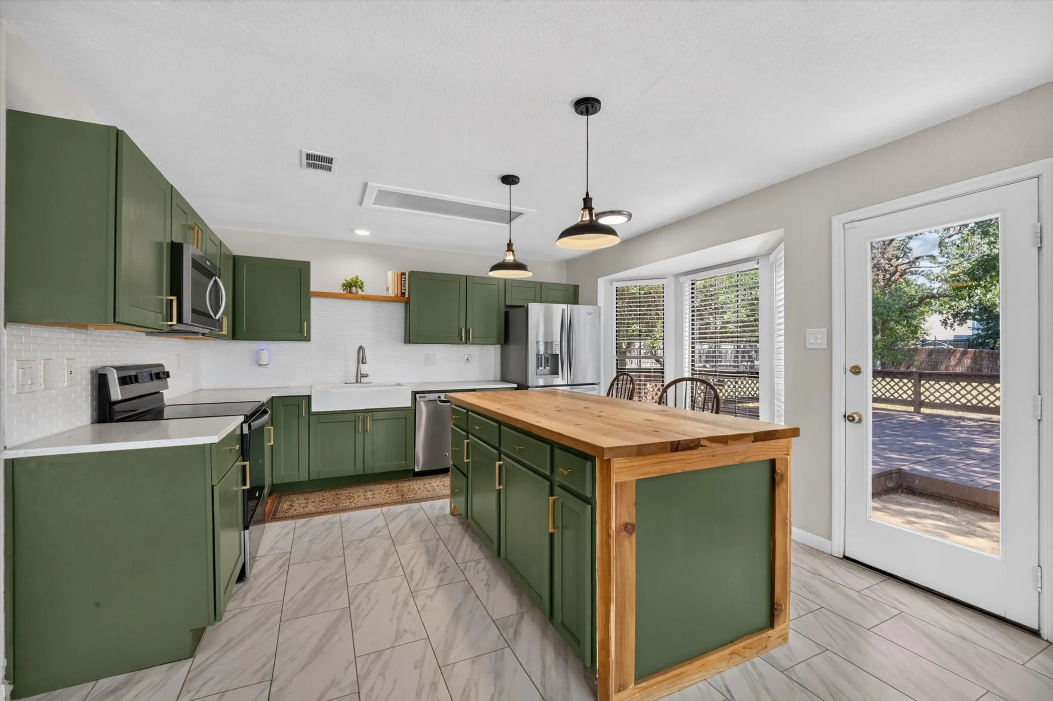 Kitchen featuring green cabinetry, wood-finish island countertop, stainless steel appliances, and white tile flooring