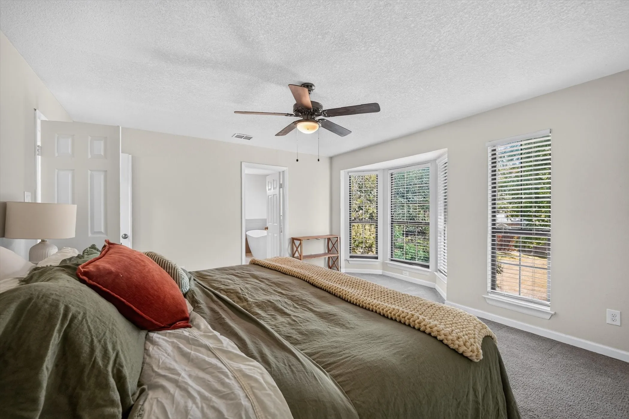 Recessed bay window, ceiling fan, carpeted flooring, and a six-panel interior door