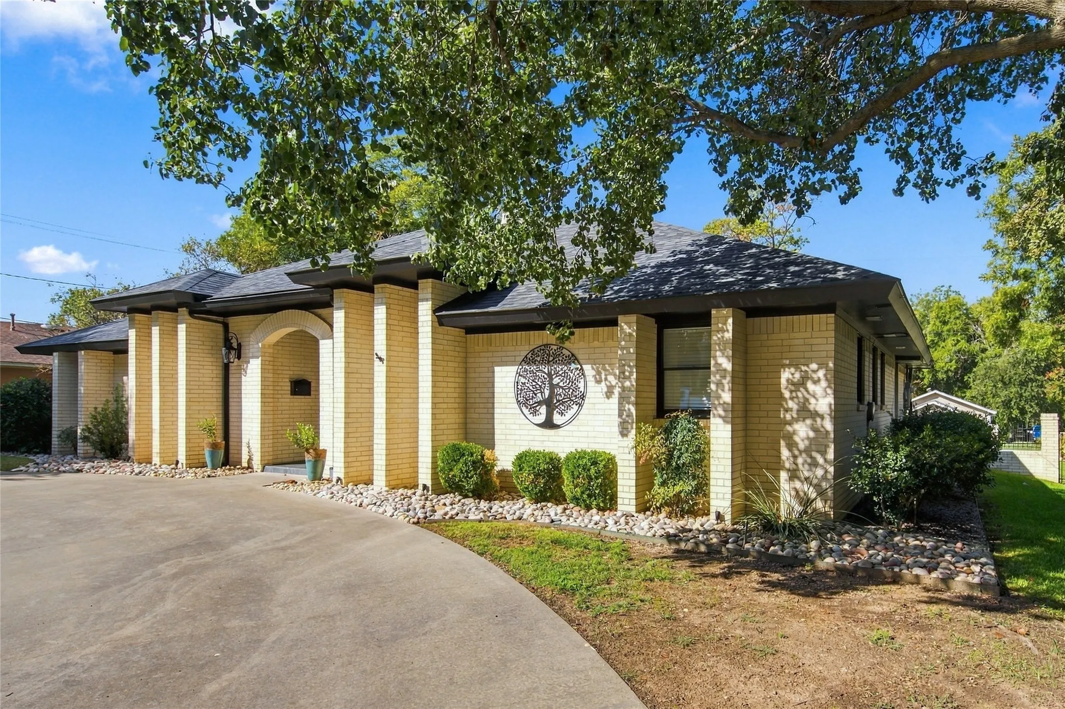 Brick exterior with an arched entryway, covered front porch, and a paved driveway