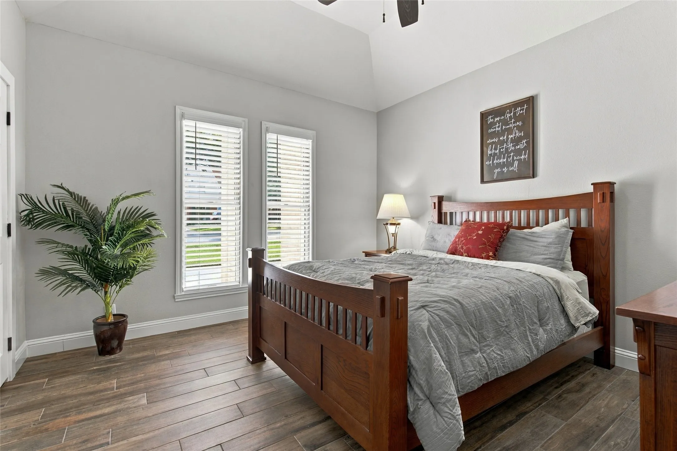 Vaulted ceiling with a ceiling fan, wood-finish plank flooring, and two windows with blinds