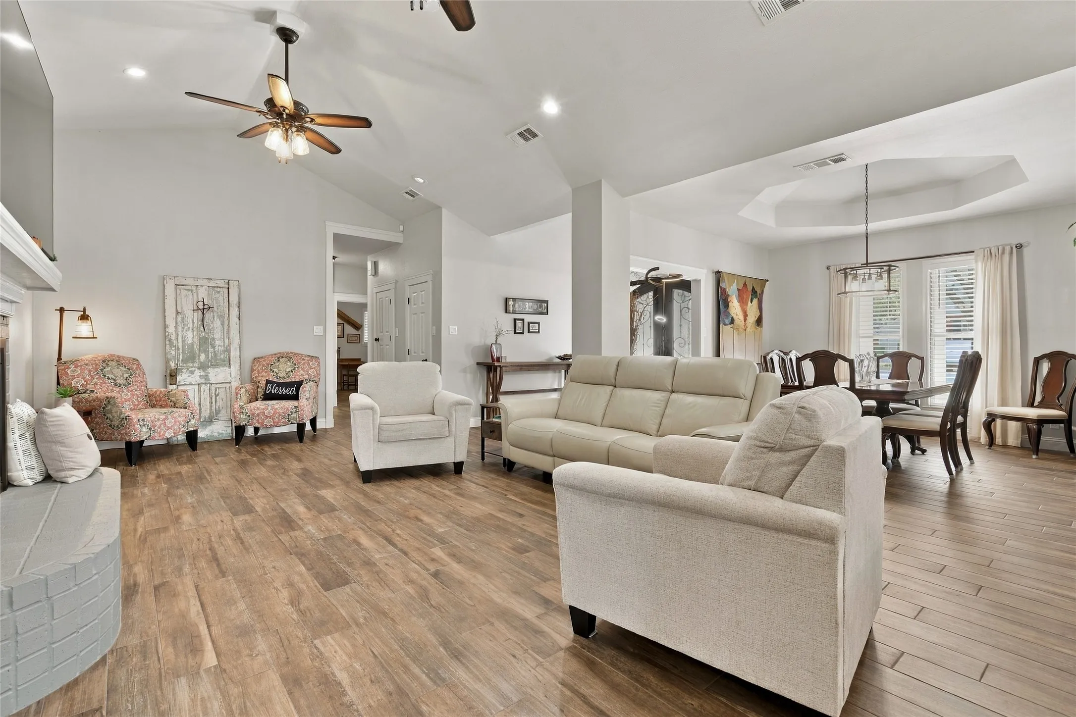 Vaulted ceilings with ceiling fans, wood-finish flooring, recessed lighting, and a tray ceiling with a chandelier