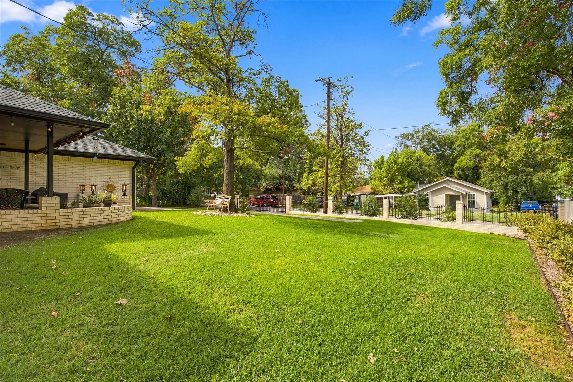 Expansive lawn area with mature trees and a brick-detailed porch