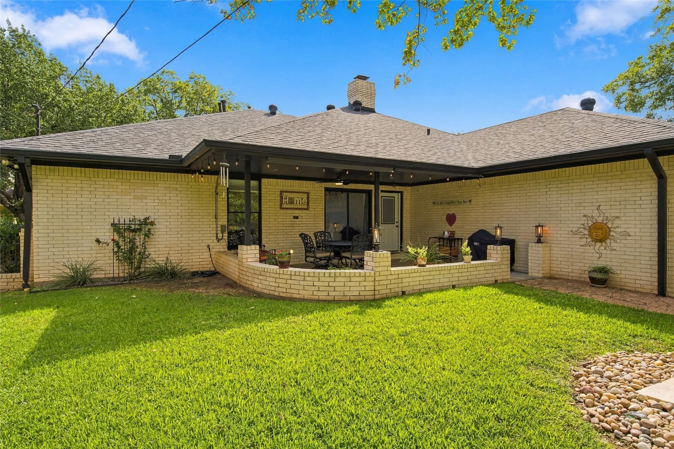Brick exterior with a covered patio, featuring a built-in planter and stone walkway