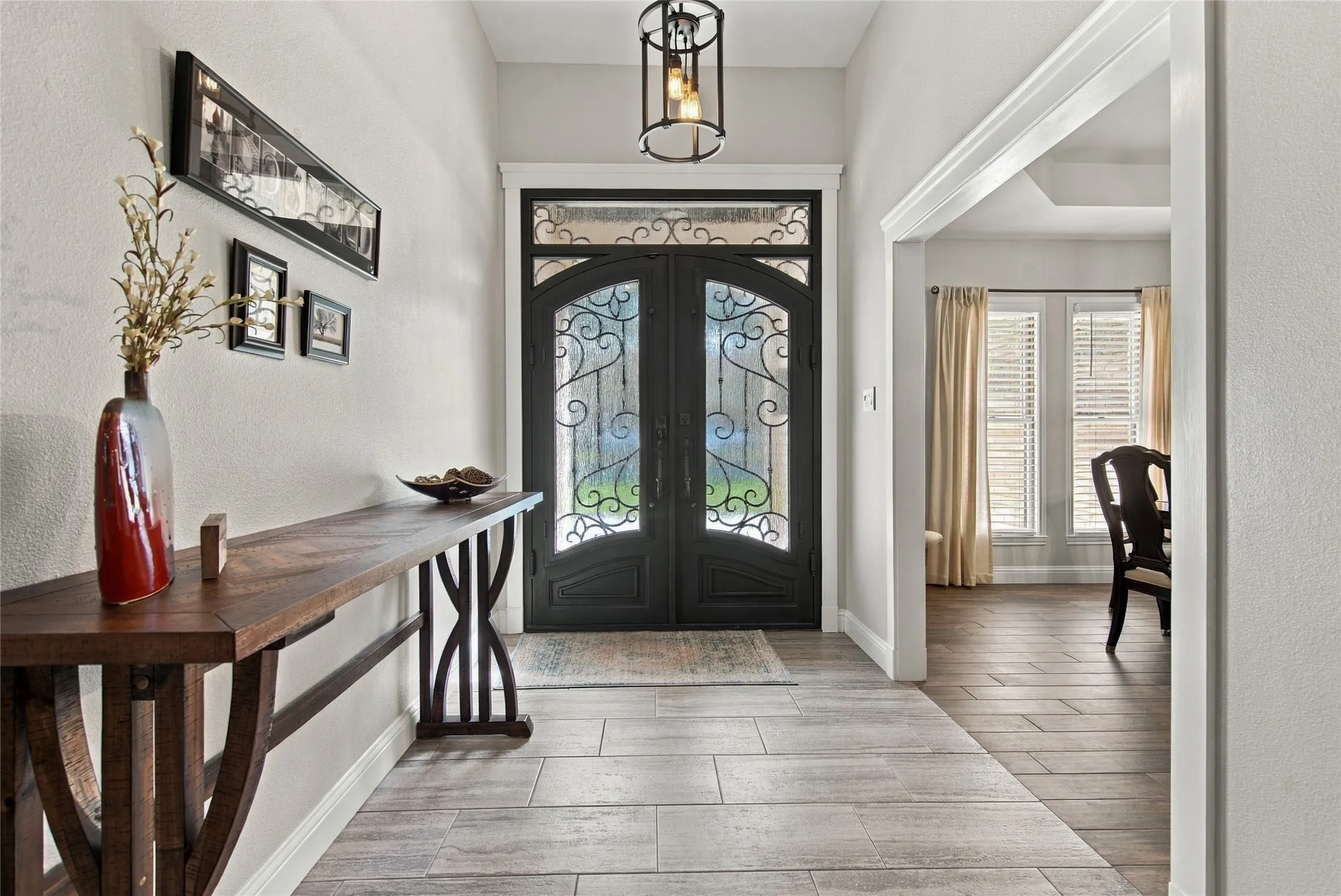 Decorative double entry doors with wrought iron detailing, light wood-finish flooring, and recessed ceiling lighting