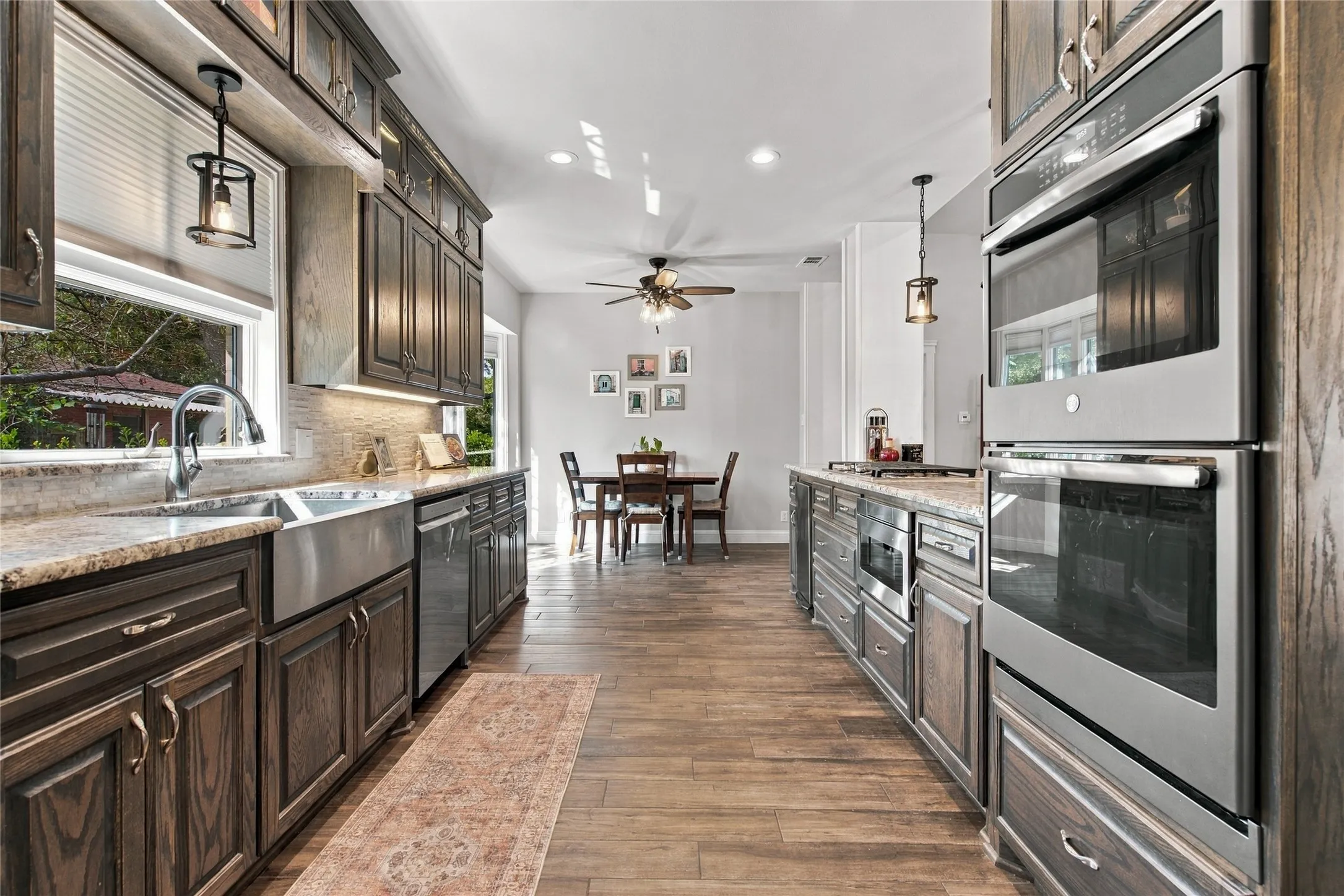 Kitchen featuring wood-finish flooring, dark wood cabinetry, stainless steel appliances, and stone countertops