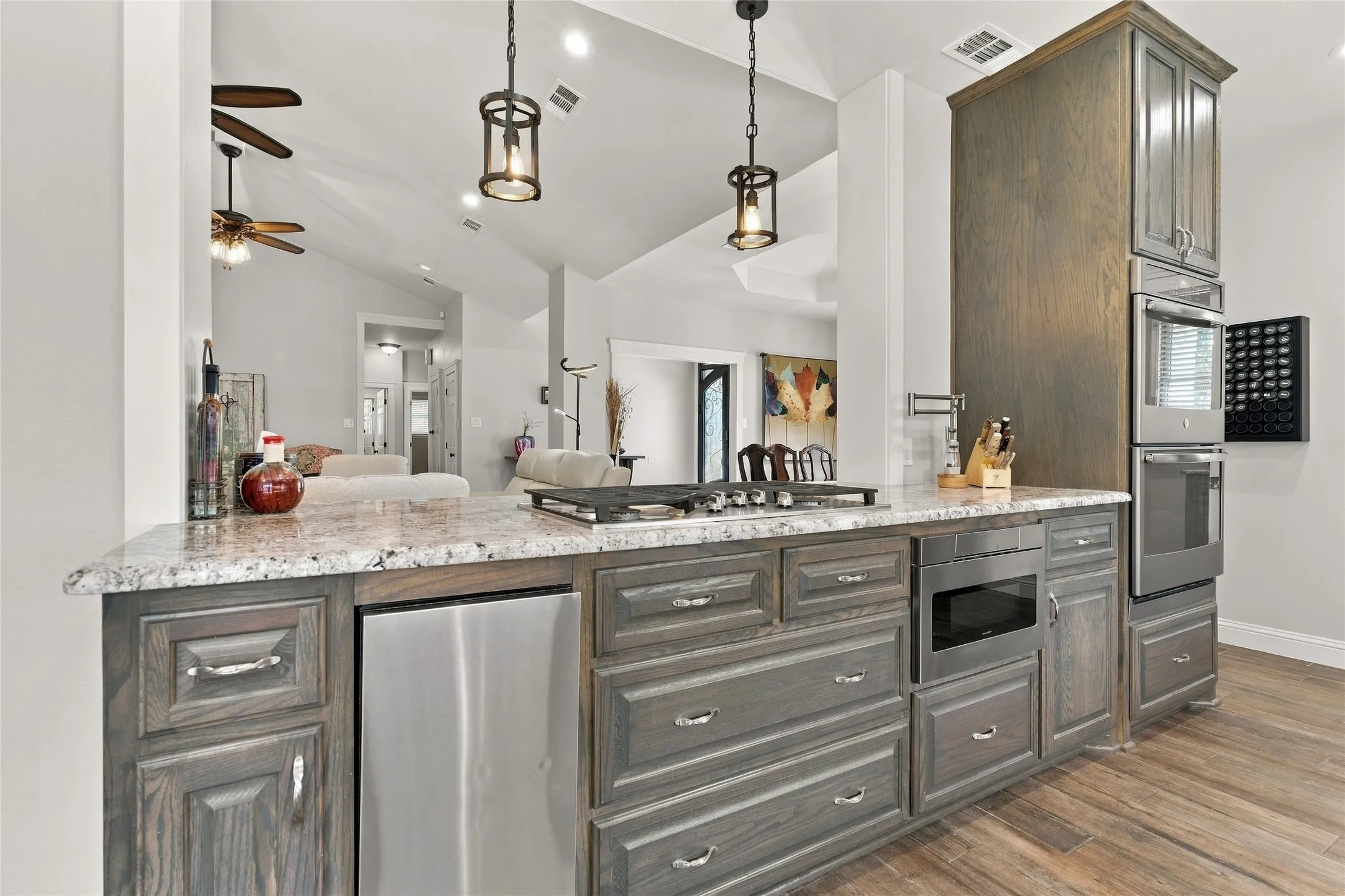 Kitchen island featuring a cooktop, built-in microwave, integrated dishwasher, and granite countertops