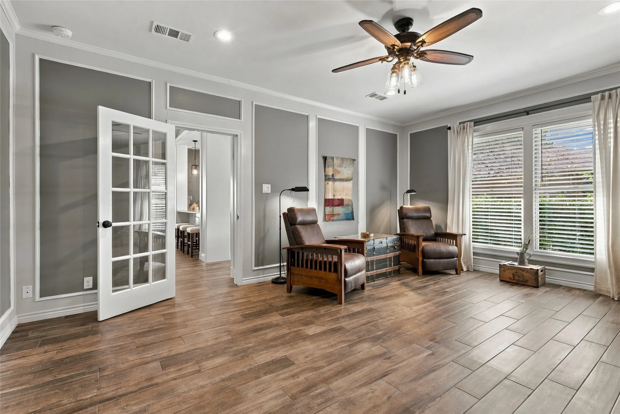 Wood-finish flooring, decorative wall molding, ceiling fan with integrated lighting, recessed lighting, and white window blinds
