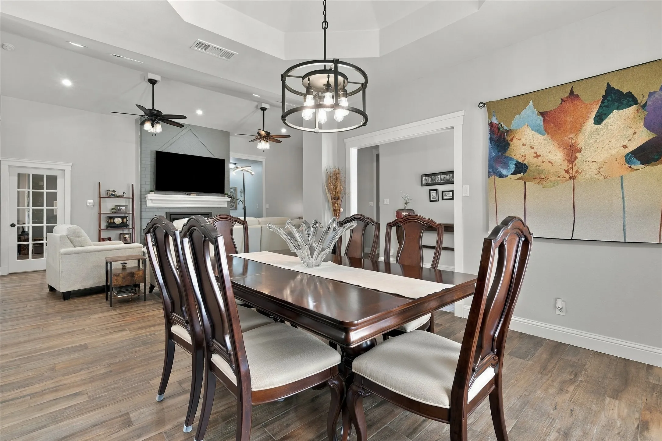 Wood-finish flooring throughout, tray ceiling with recessed lighting, and a contemporary chandelier