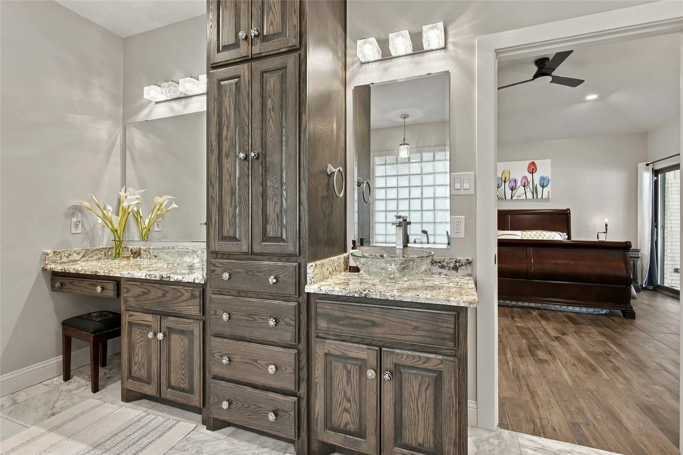Dual vanity with granite countertops, wood-finish cabinetry, and vessel sinks
