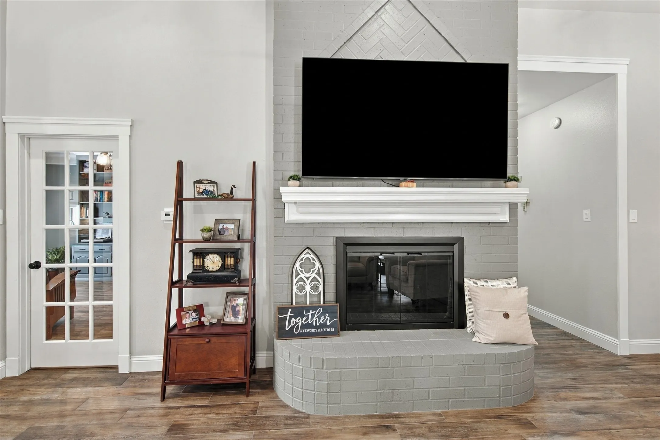 Fireplace with a brick surround and hearth, featuring a white mantel, set against a herringbone-patterned wall