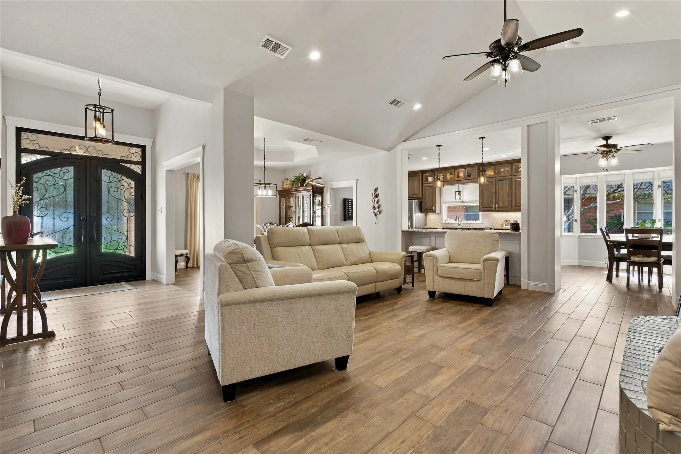 Vaulted ceilings with recessed lighting, wood-finish tile flooring, and custom double entry doors