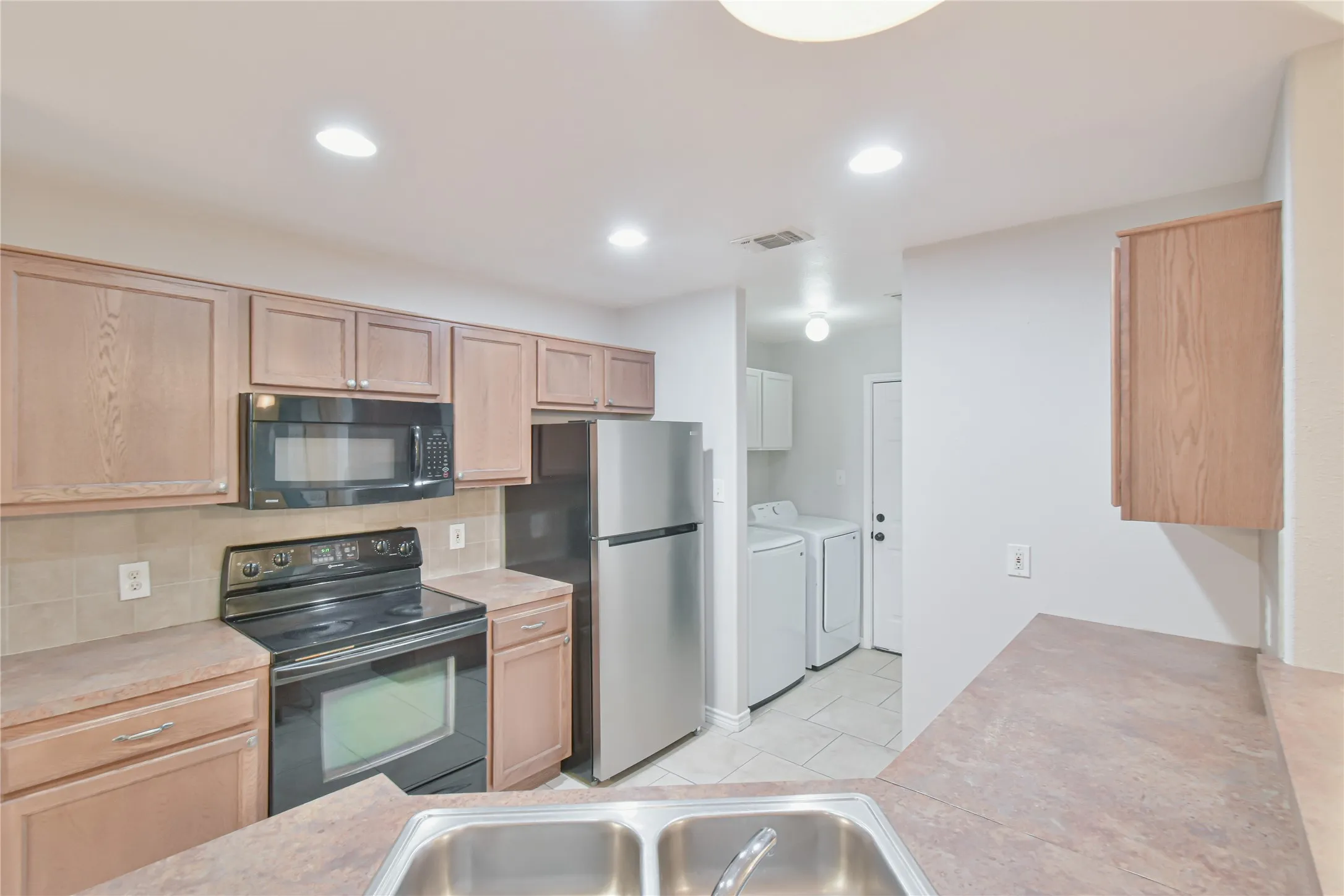 Kitchen featuring wood-finish cabinetry, stainless steel appliances, and a double basin sink