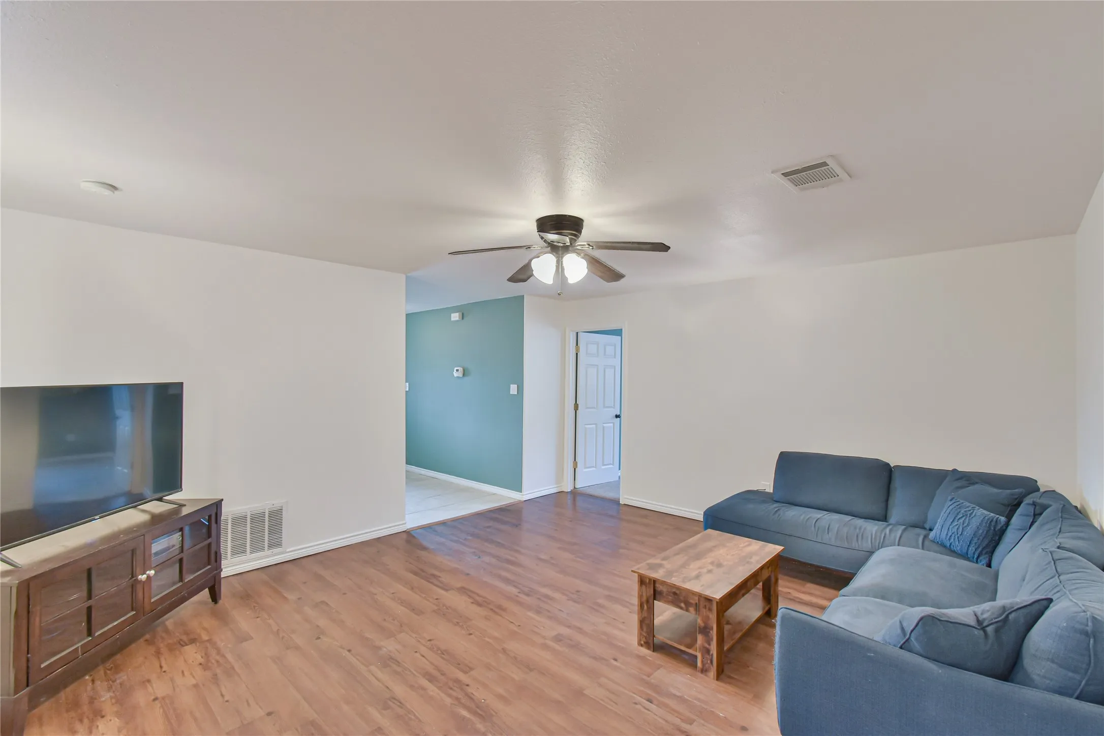 Spacious living area featuring wood-finish flooring, a ceiling fan, and recessed lighting