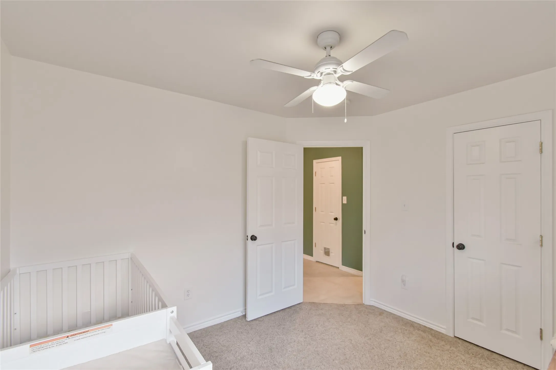 Light-colored carpeting, white walls, and a ceiling fan with integrated lighting