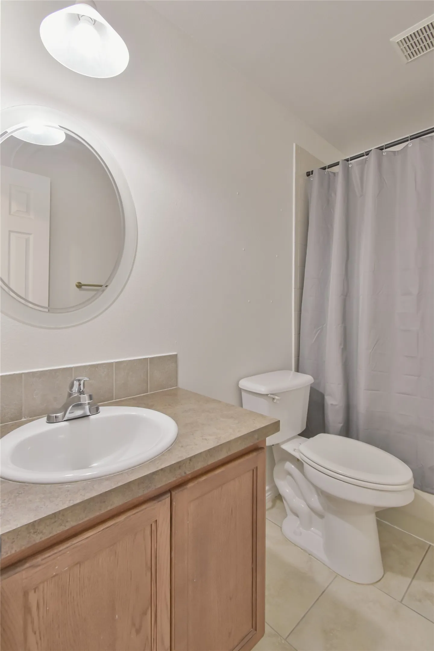Vanity with integrated sink, tile flooring, and a full shower/tub combination