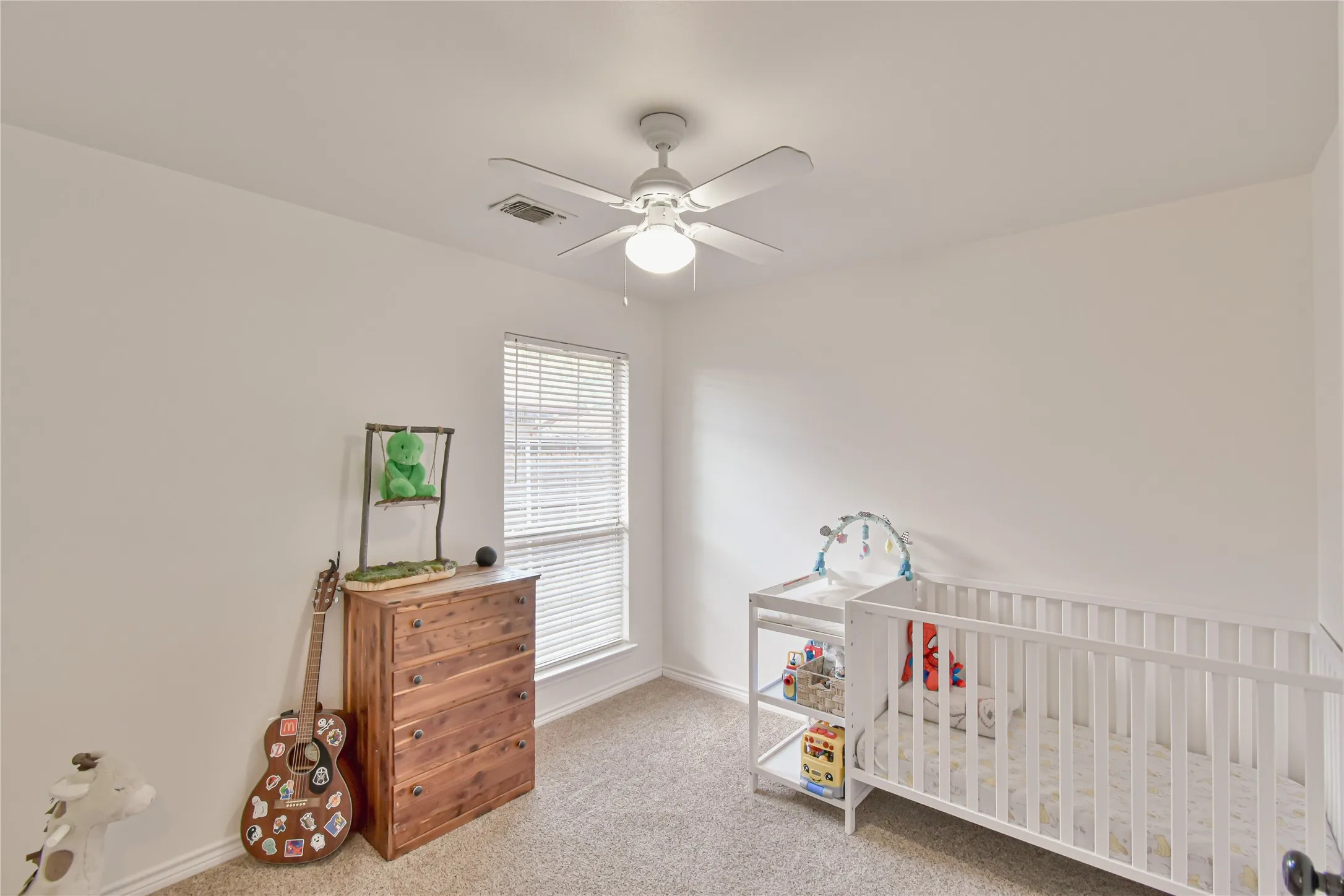 Carpeted room featuring a ceiling fan with light, a window with blinds, and white painted walls