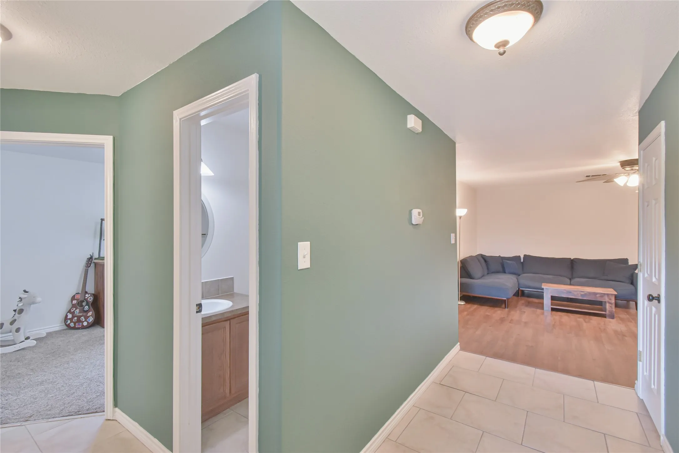 Tile flooring in the entryway, leading to a living area with wood-finish flooring