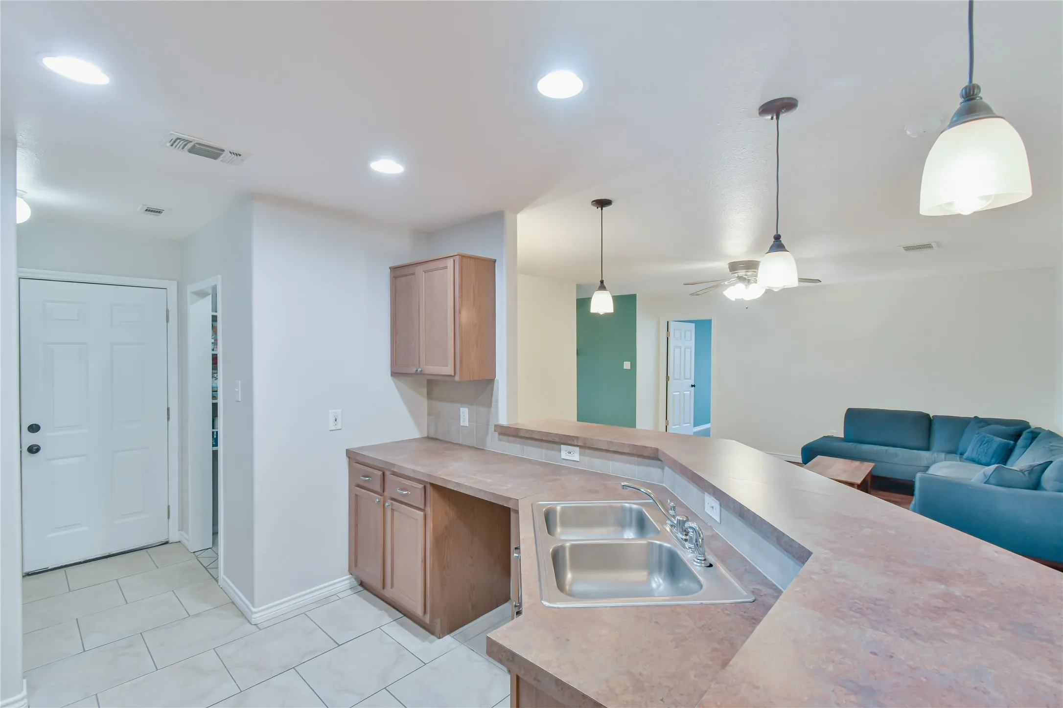 Kitchen features a stainless steel double sink, wood-finish cabinetry, and solid surface countertops