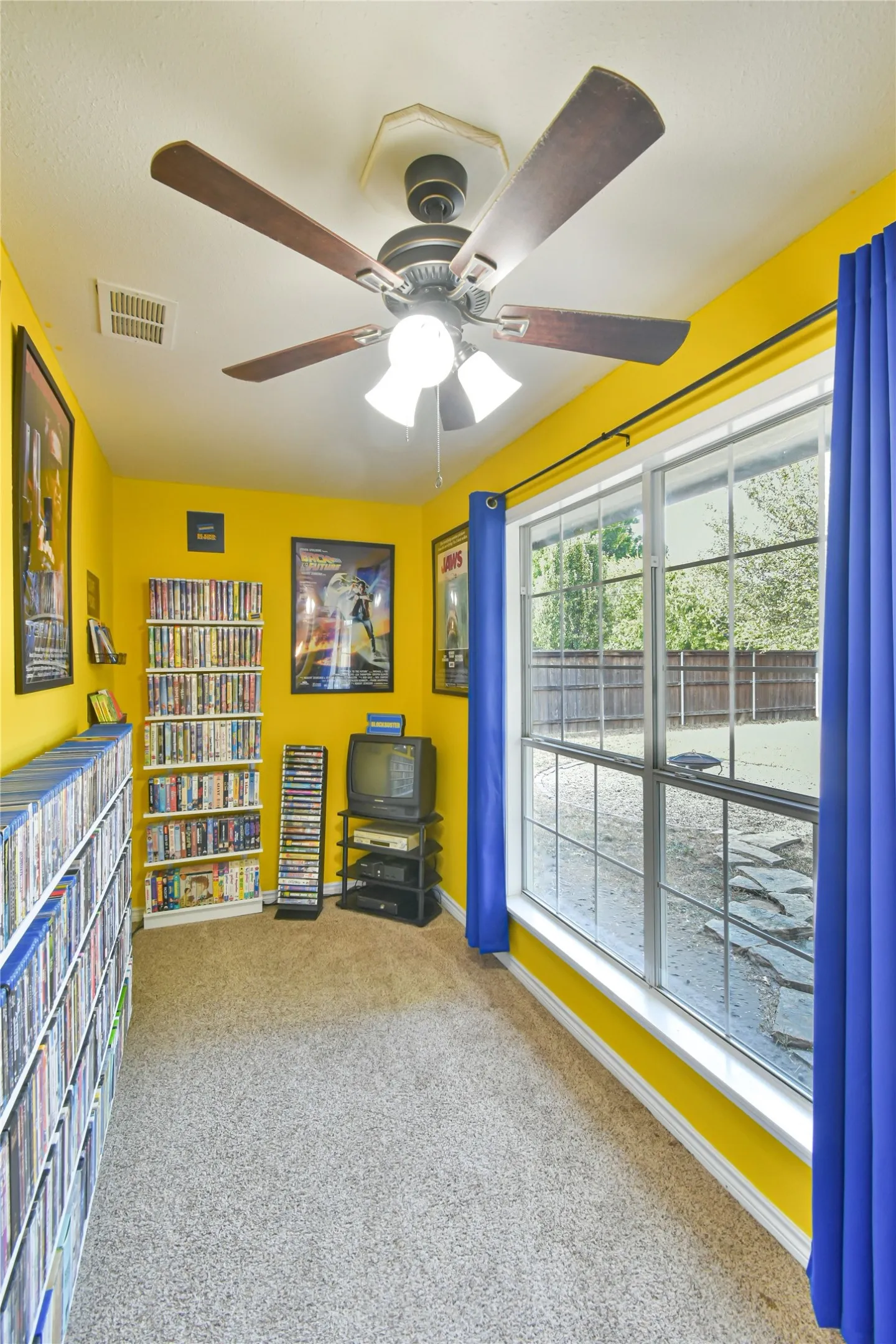 Window with grid pattern, overhead ceiling fan, and light-colored carpet flooring
