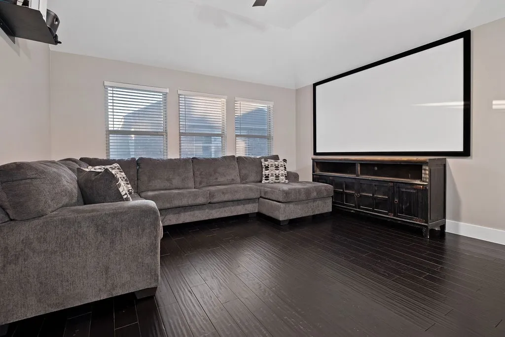 Dark wood-finish flooring, vaulted ceiling, built-in projection screen, built-in media console, and three large windows