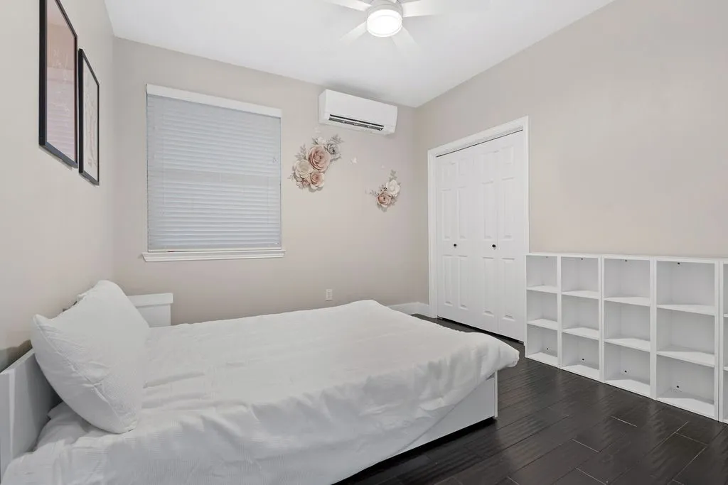 Dark wood-finish flooring, white walls, and a white ceiling fan with integrated lighting