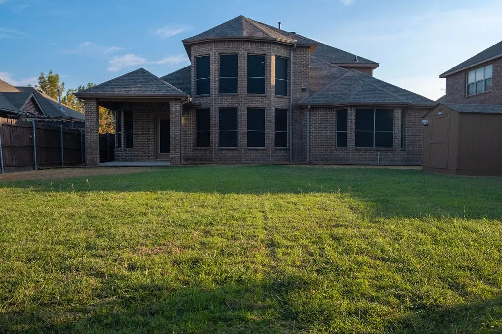 Expansive backyard featuring a brick exterior, covered patio, and privacy fencing