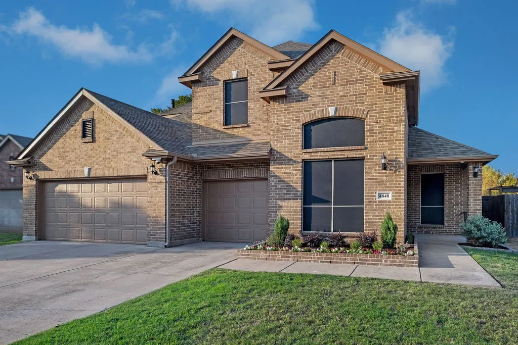 Brick exterior, multiple gables, arched window, two-car garage, established landscaping