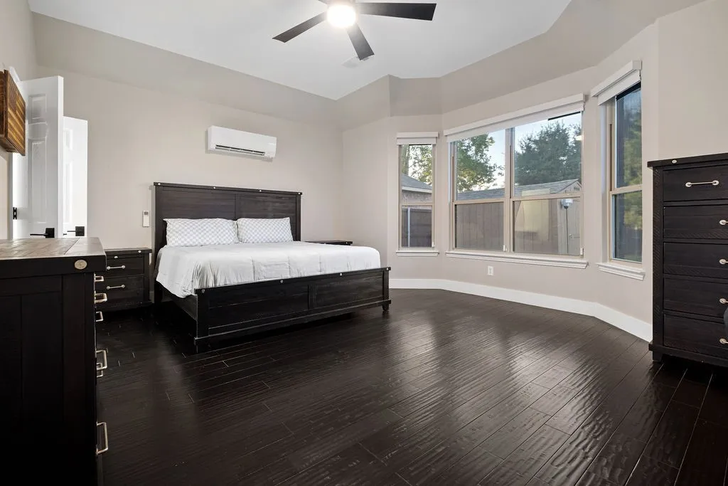 Wood-finish flooring, bay window with multiple panes, ceiling fan, and high ceilings