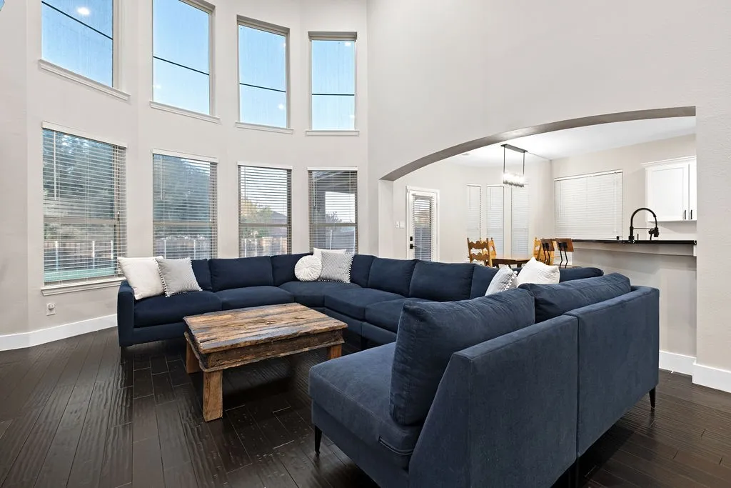 Vaulted ceiling, dark wood-finish flooring, multiple large windows, arched entryway, and a breakfast bar with an undermount​​‌​​​​‌​​‌‌​‌‌​​​‌‌​‌​‌​‌​​​‌​​ sink
