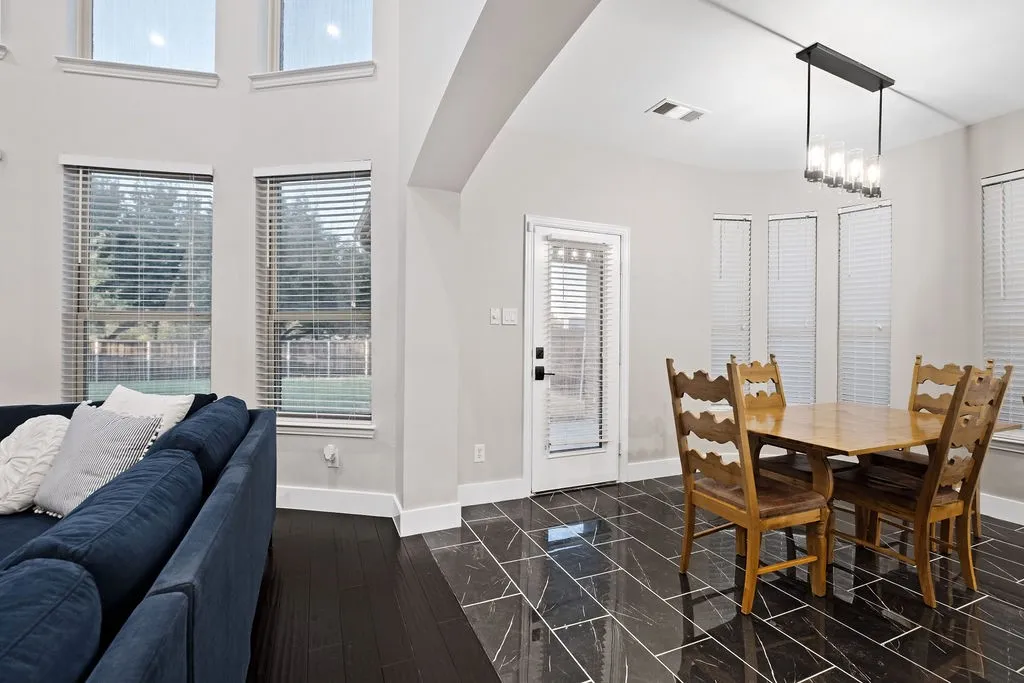 High ceilings, dark wood-finish flooring, and a modern linear chandelier