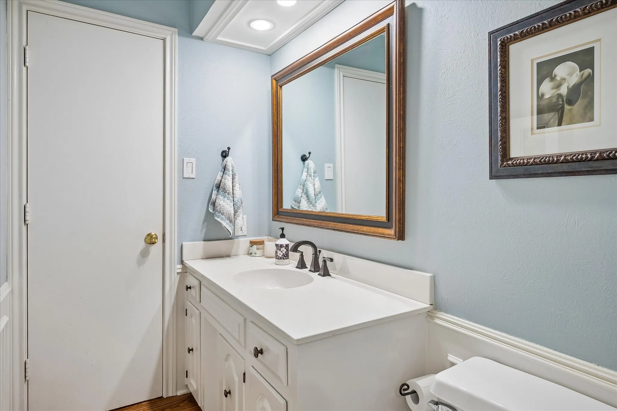 White vanity with under-sink storage, integrated basin, and dark bronze-finish fixtures