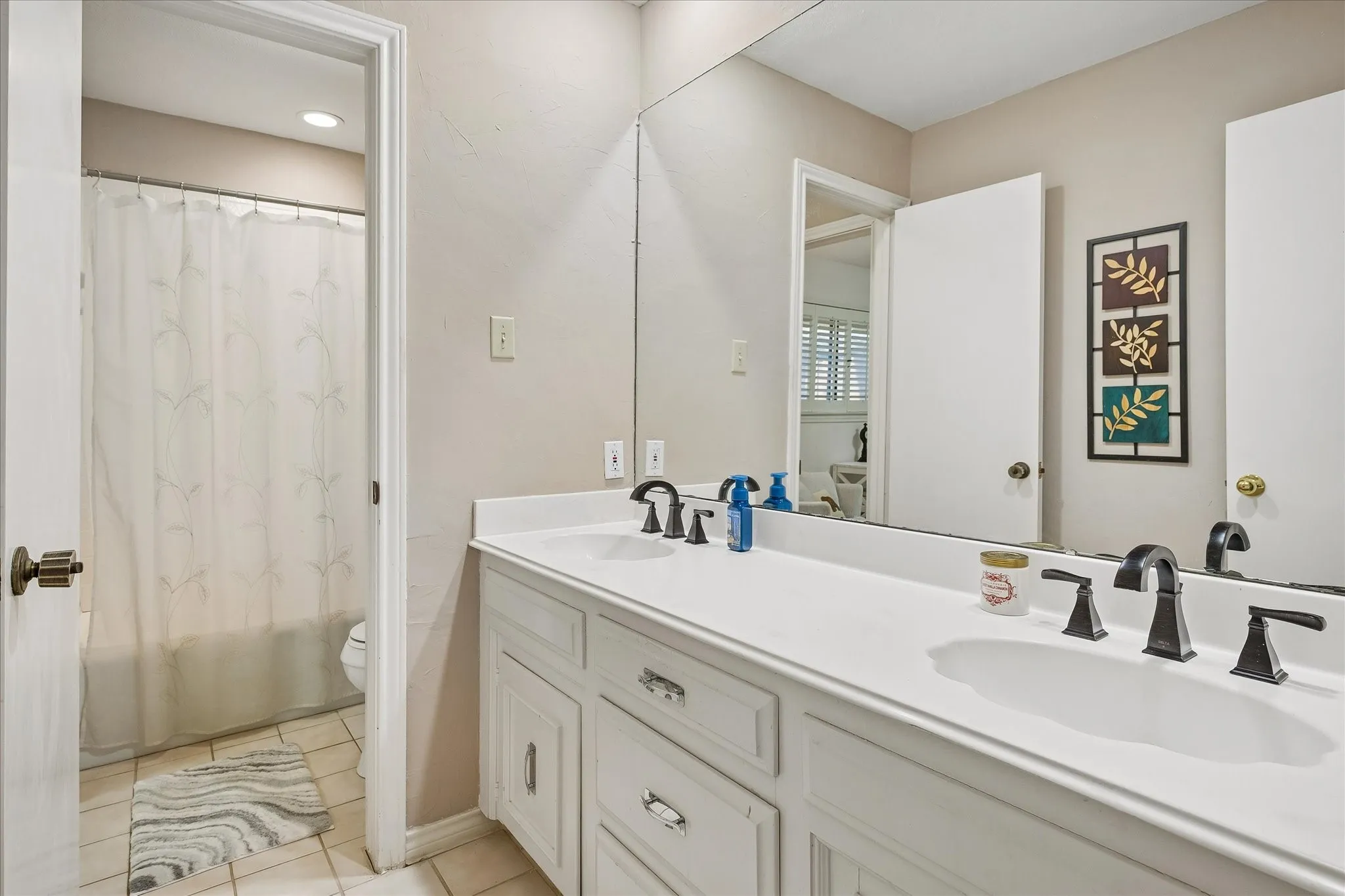 Dual vanity with white cabinetry, solid surface countertop, and dark-finish hardware
