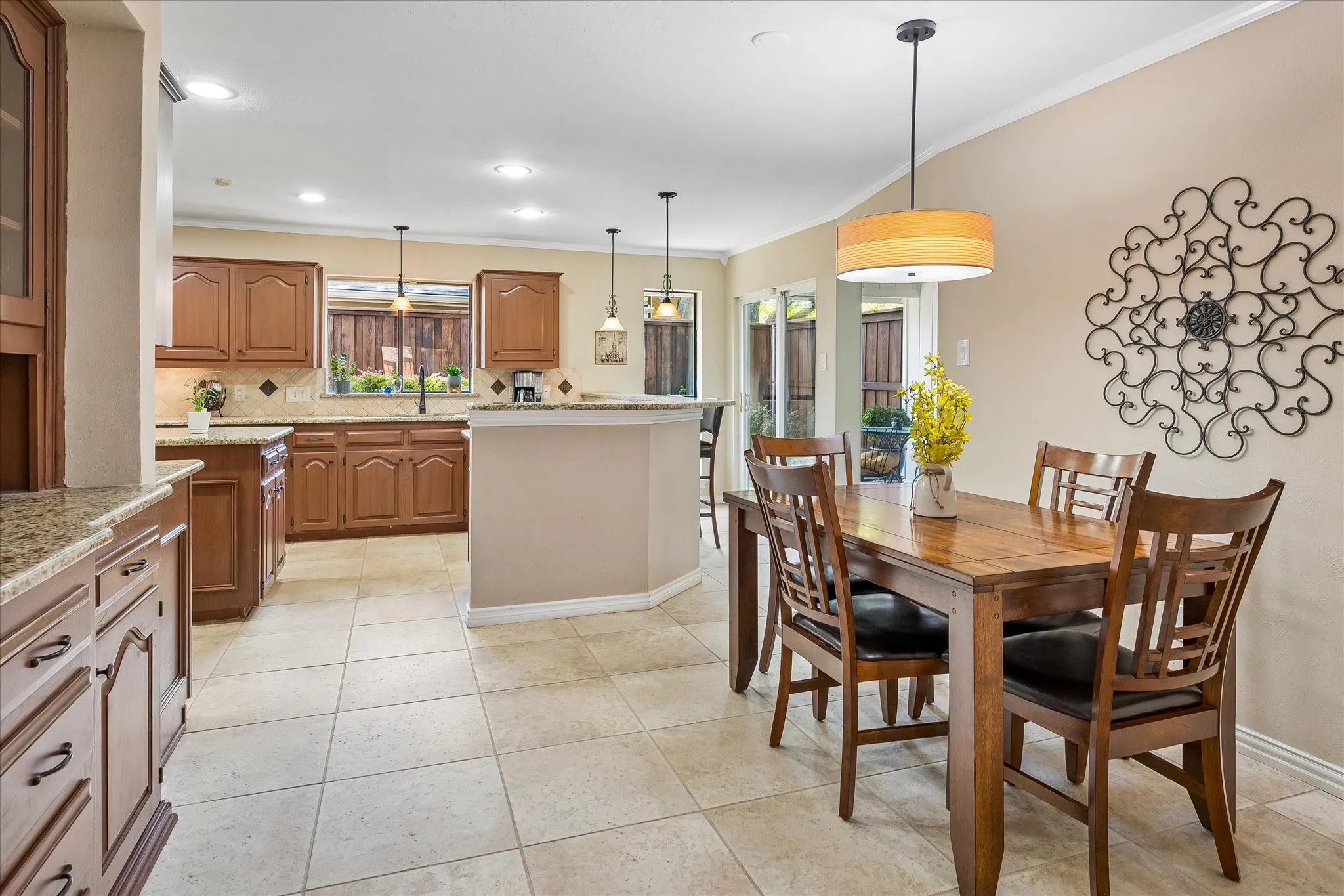 Kitchen and dining area featuring wood cabinetry, stone countertops, tile flooring, and recessed lighting