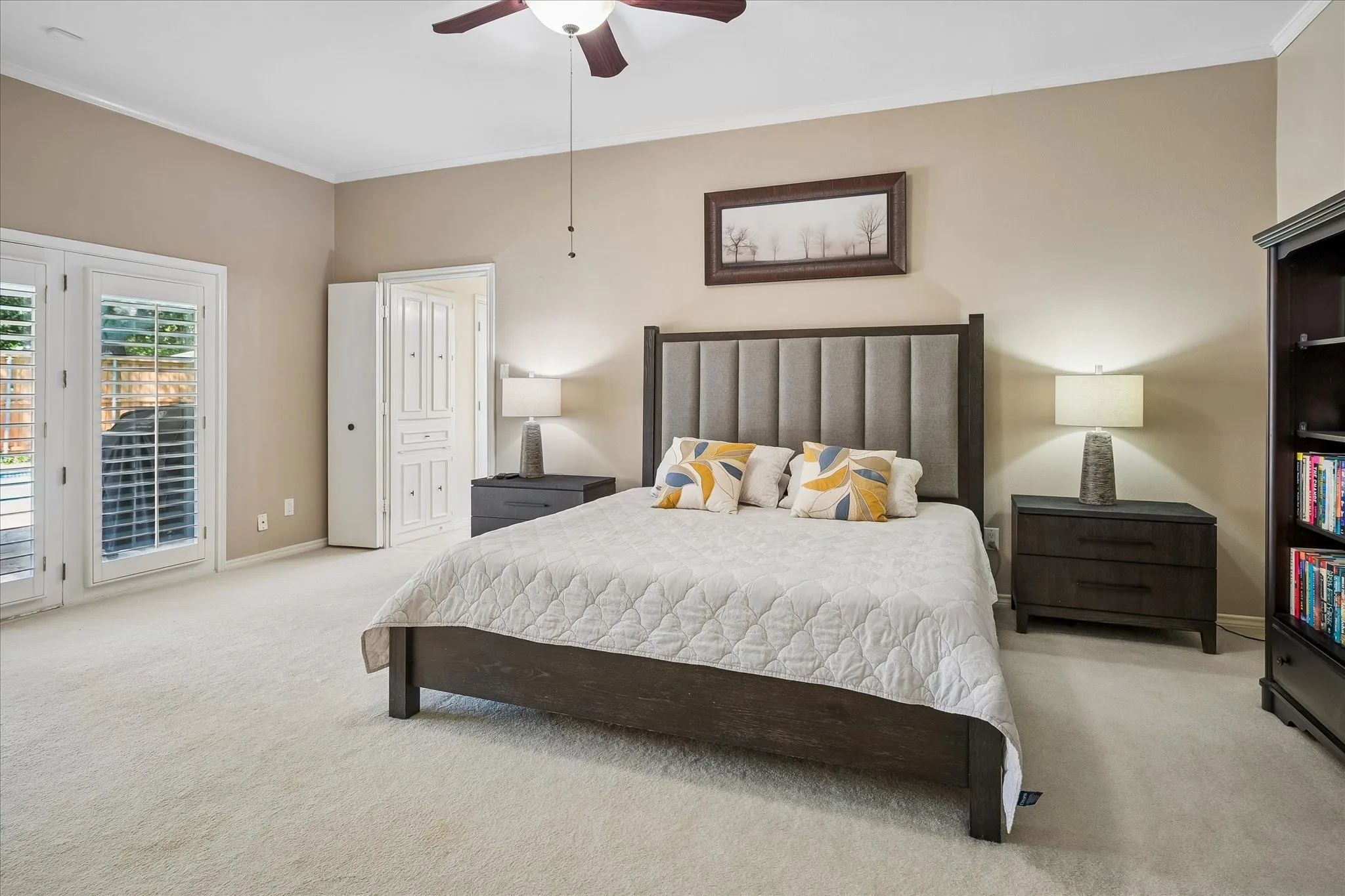 Ceiling fan with light fixture, light-colored carpeting, white paneled double doors, white interior door, and neutral wall paint