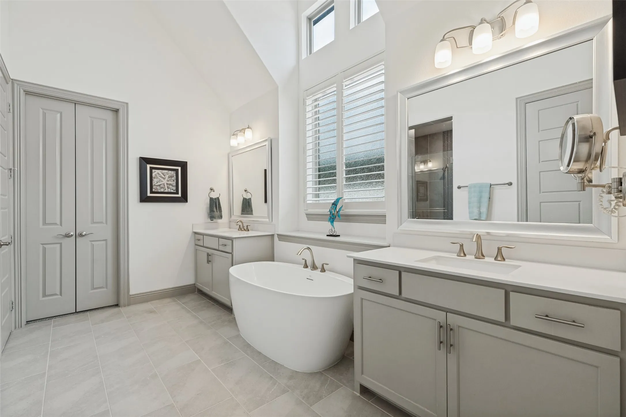 Luxurious master spa bath with vaulted ceiling,  soaking tub and double sinks. French doors leading into expansive master closet