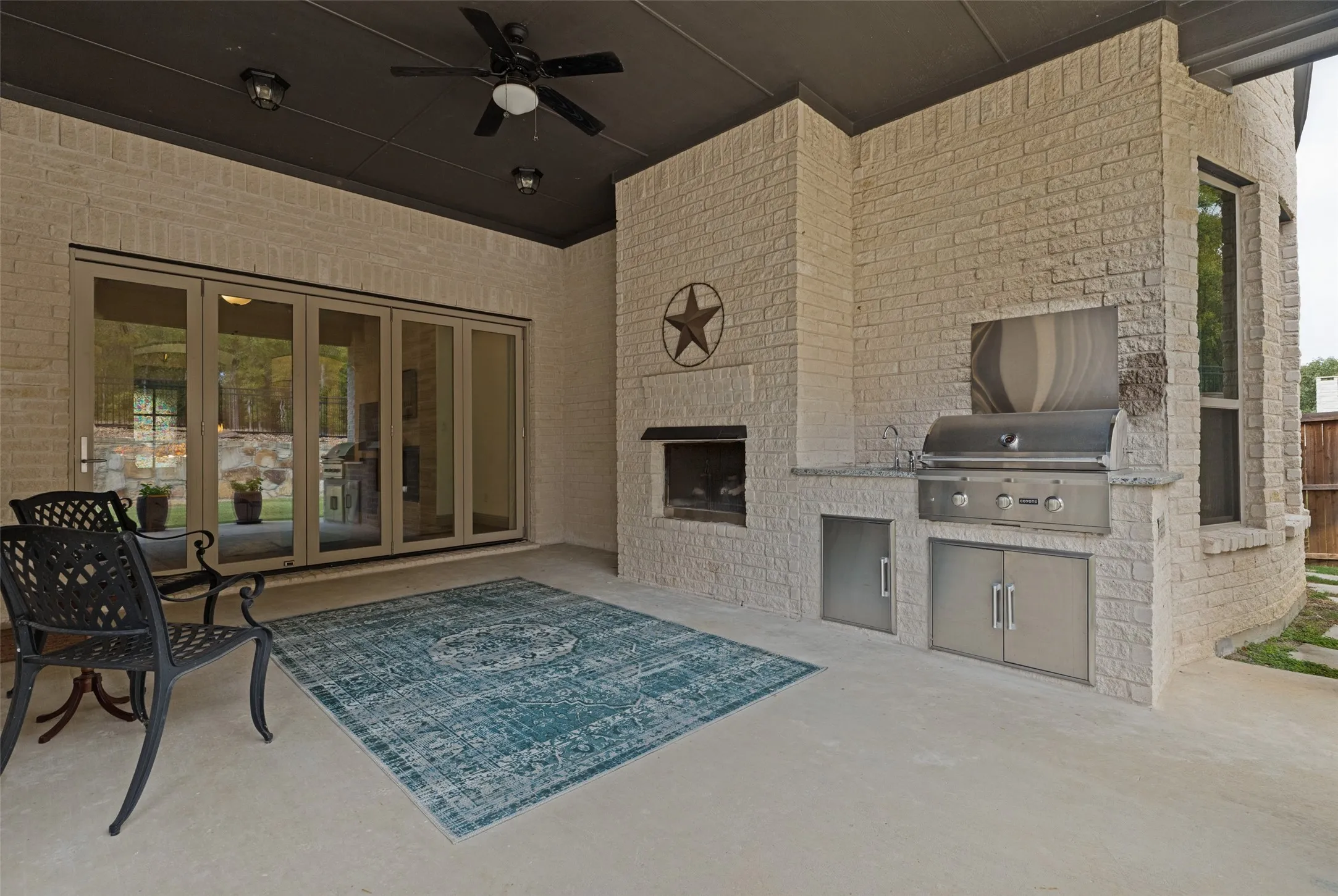 Large seating area with gas fireplace, built in grille and view of bi-fold doors off the living from provides peaceful indoor outdoor living